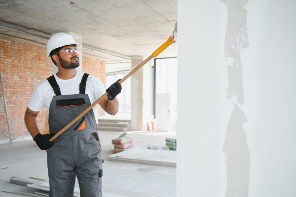 Indian Painter painting the office wall with roller paint.